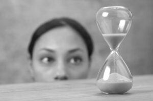 Person schaut auf Sanduhr mit rieselndem Sand