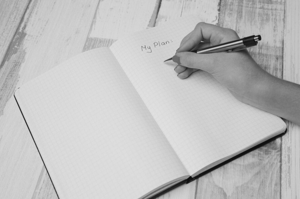 schreibende Hand über Notizbuch - Plan machen für die Nachfolge